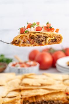 a piece of taco cake being held by a fork over tortilla chips