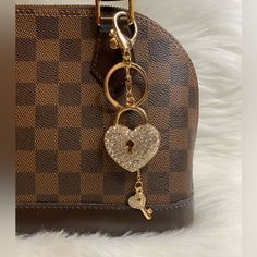 a brown purse with a heart shaped keychain hanging from it's side