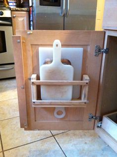 a kitchen cabinet with a cutting board in it