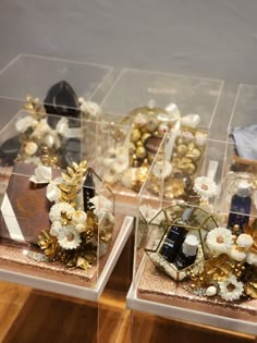 three clear boxes filled with different types of items on top of a wooden floor next to each other