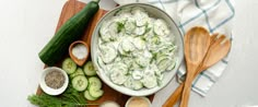 cucumbers and other ingredients are arranged on a cutting board with wooden spoons