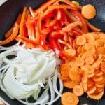 chopped carrots and onions in a frying pan