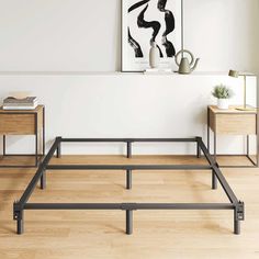 the bed frame is made from metal and has two nightstands on each side, along with a painting above it