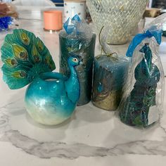 three candles are sitting next to each other on a table with peacock figurines