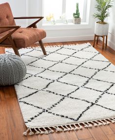 a white rug with black squares and tassels on the floor next to a chair