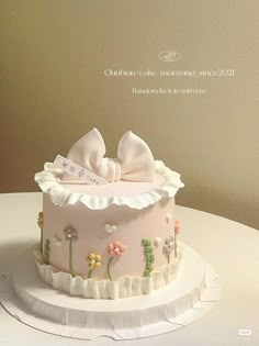 there is a pink cake with white flowers on the top and a bow in the middle