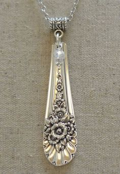 a silver pendant with flowers on it sitting on top of a cloth covered tablecloth