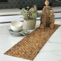 a place mat on a kitchen counter with plates and bowls next to it in front of a potted plant