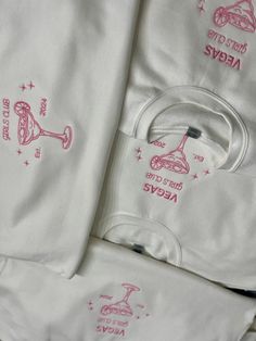 several white shirts with pink designs on them