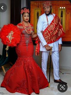 the man and woman are dressed up in traditional african garb, with red feathers on their head