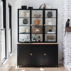 a shelf with vases and other items on it in front of a brick wall