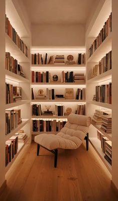 a room filled with lots of books on shelves next to a white couch and chair