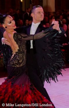 a man and woman dressed in black and red dancing