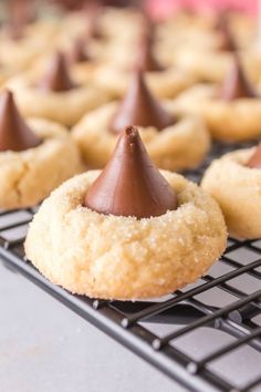 some cookies with chocolate frosting and a cone on top are sitting on a cooling rack