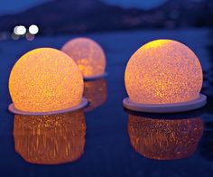 three glowing balls sitting on top of a table next to each other in the water