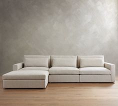 a white couch sitting on top of a hard wood floor next to a gray wall