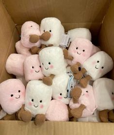 a cardboard box filled with lots of white and pink stuffed animals on top of each other