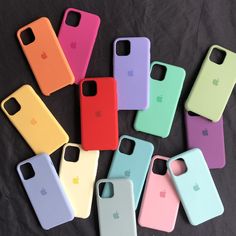 several different colored iphone cases sitting on top of a black cloth covered table next to each other