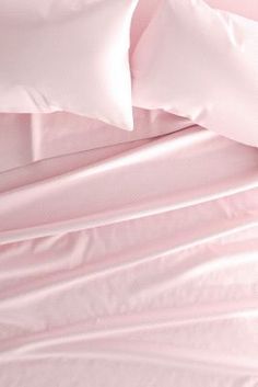 a bed with pink sheets and pillows on top of it, next to a pillow