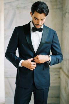 a man in a tuxedo adjusting his bow tie