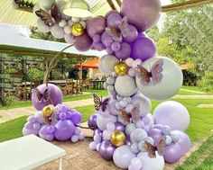 some balloons are hanging from the ceiling in front of a table with flowers and butterflies on it