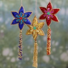 three christmas ornaments hanging from strings with tassels and bead work on them