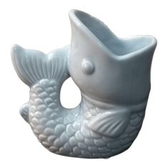 a white ceramic fish shaped vase sitting on top of a table