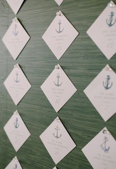 wedding seating cards with an anchor on them are hung on a wall in the reception room