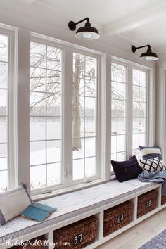 a white room with large windows and lots of pillows on the window sill next to it