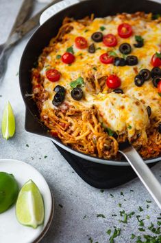 a casserole dish with cheese, olives, tomatoes and other toppings