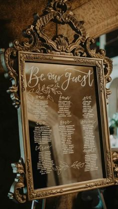 a wedding seating chart is displayed in front of an ornate frame on a table at a reception