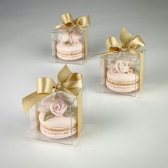 three clear boxes with pink and gold decorated cakes in them, one has a bow