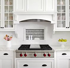 a stove top oven sitting inside of a kitchen next to white cabinets and counter tops