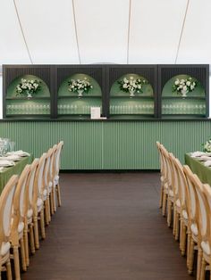 the tables and chairs are set up in front of the wall with flowers on them