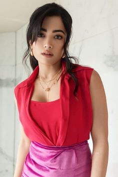 a woman in a red top and purple skirt posing for the camera with her hands on her hips