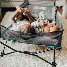 two dolls laying in a baby crib on top of a white carpeted floor