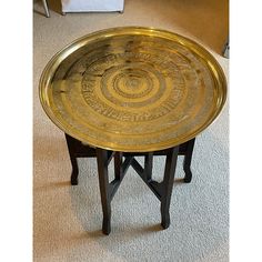 a gold plate sitting on top of a wooden table next to a white carpeted floor