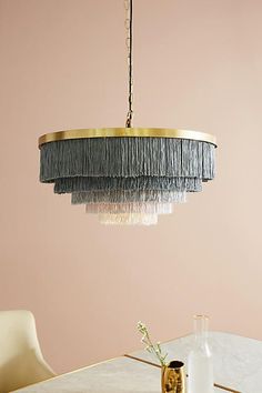 a chandelier hanging over a dining table in a room with pink walls and white chairs