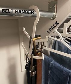 there is a coat rack with clothes hanging from it's hooks and the name belt hanger attached to it