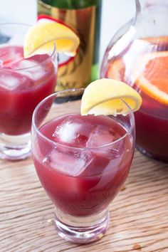 two glasses filled with red liquid sitting on top of a wooden table