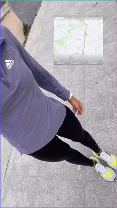 a woman in purple shirt and black leggings standing on sidewalk next to map