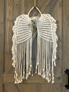 a wall hanging made out of white yarn with an angel wings design on the front