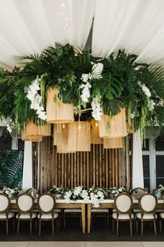 the table is set up with white flowers and greenery on it, along with chairs