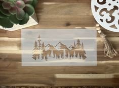 a wooden table topped with a cutting board covered in paper cut outs and pine trees