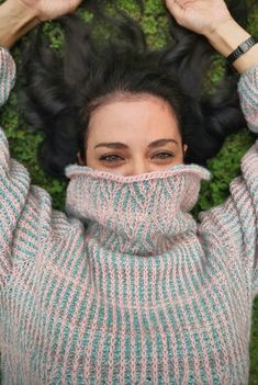 a woman with her hands on her head is covering her face from the wind while laying in grass