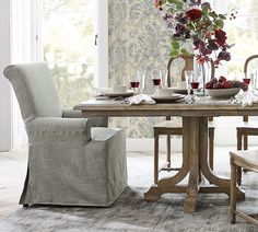 a dining room table set with place settings and flowers in vases on the table