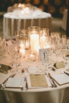 the table is set with wine glasses, place cards and candles for an elegant wedding reception