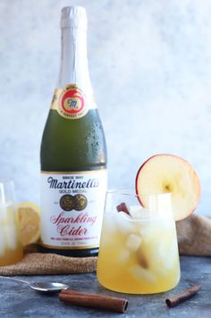 an apple cider next to a bottle of wine and two glasses filled with liquid