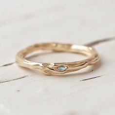 a close up of a gold ring on a white surface with a blue diamond in the middle