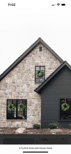 a gray house with wreaths on the windows and two christmas wreaths in the window